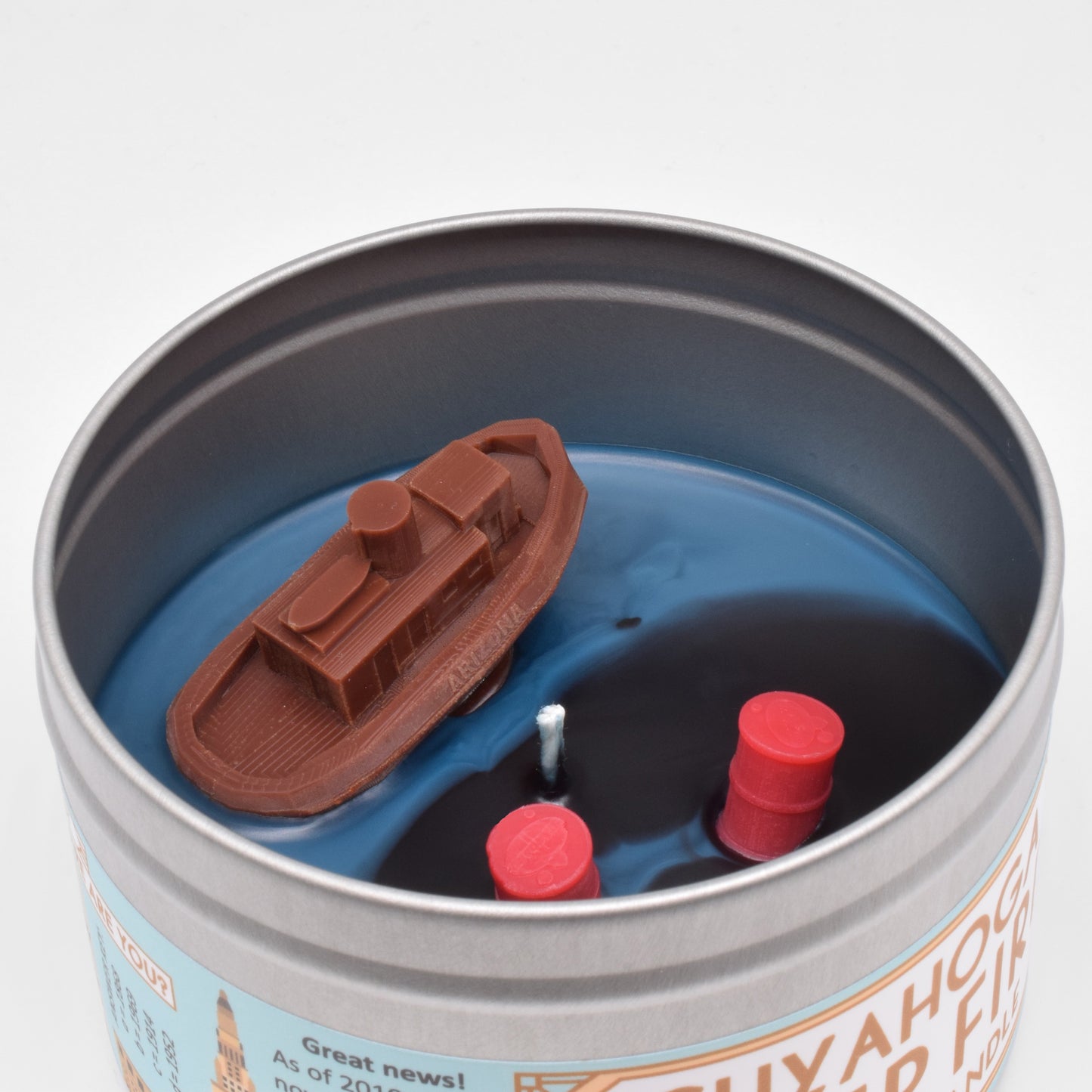 The surface of the candle has a wax embed of the tugboat Arizona and of an oil spill.