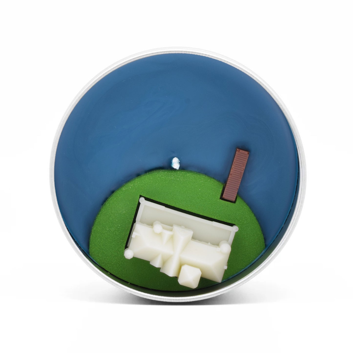 An overhead view of the candle, showing the Gatsby mansion atop a grassy lawn with a dock reaching out into the water.